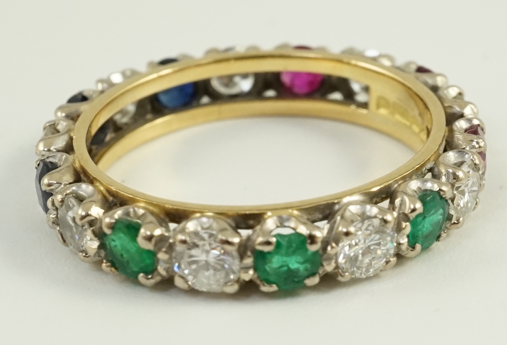 A modern 18ct gold, ruby, sapphire, emerald and diamond set full eternity ring